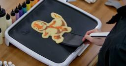 Charmander Pancake Art step 10.1: When your pancake is loose from the griddle, it's time to flip! With confidence, slide your spatula under the pancake...