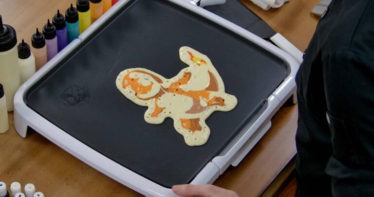 Charmander Pancake Art step 9.1: Once you're done drawing and filling your design, set the griddle to approximately 225 degrees fahrenheit. As your pancake cooks, you'll see bubbles appear like in this image.