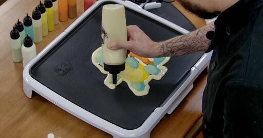 Squirtle Pancake Art step 6.2: Surround the design entirely with plain batter (we're using the Dancakes fill bottle here, which has a much wider aperture and pours faster).
