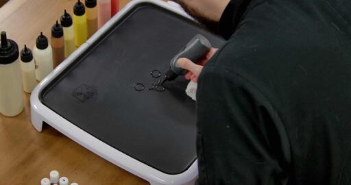 Pikachu Pancake Art step 1.1: Begin by drawing the outlines of Pikachu's facial features - the eyes, the dot for the nose, and that cute mouth!