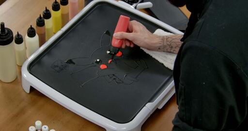 Pikachu Pancake Art step 3.2: While holding that red batter pen, go ahead and color in the top of pikachu's mouth. Draw a curved line to mark the tongue, and color everything above that.