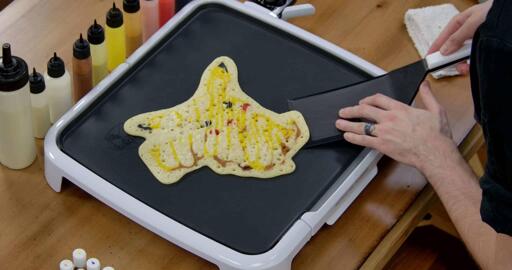 Pikachu Pancake Art step 8.2: As your pancake cooks you'll see bubbles appear and pop on the back of it. This is great! You want to see bubbles appear on the whole back, and for that shiny 'wetness' to subside. Once the pancake looks less shiny and has bubbles all across it, you can start gently nudging it with your spatula through what we call 'carving'. Work your way around the outside edge of the pancake without forcing it; it should release all by itself.