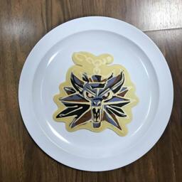 An image of a pancake drawn in the shape of Geralt's Medallion from The Witcher novel and video game series.