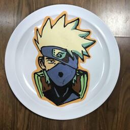 An image of a pancake drawn in the shape of Kakashi, from the Naryto series.