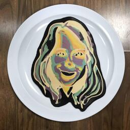 An image of a pancake drawn in the shape of a woman using negative colors, to create a strange psychedelic effect.