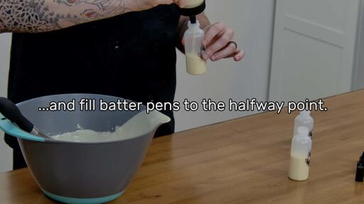 This image shows pancake batter being poured from a fill bottle into a batter pen, and says