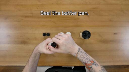 An image of the artist sealing the batter pen by screwing the tip and cap into place firmly. The image reads
