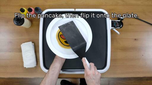 An image of the heart eyes emoji pancake design being flipped onto the plate. The image reads: