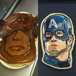 A side-by-side image of two pieces of pancake art. On the left, a large, cartoonish Captain America design has been crafted using browned and burned pancake batter lines to create contrast. The design is resting on a diner platter atop a stainless steel countertop. On the right side of the image, is a beautiful, full-color portrait of Captain America as portrayed by the actor Chris Evans. This design rests on a black background and has multiple shades of blues, grays, browns and red building up a lovely, semi-realistic rendition of the subject matter.
